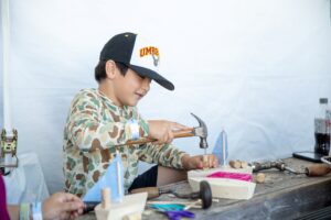 Kid working on wooden toy boat